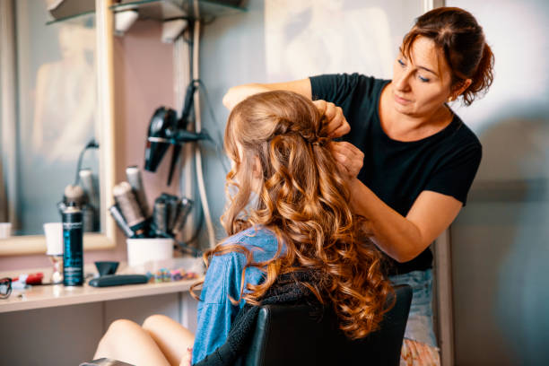 Caucasian brunette teenage girl with long hair at hairstylist. Making curly hair style. Copy space